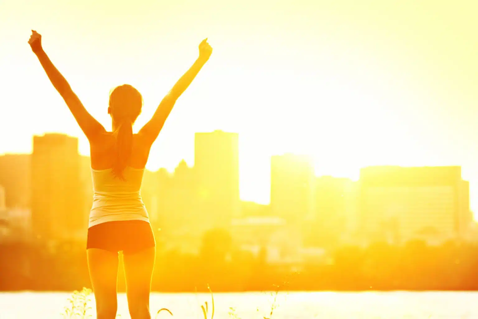 a woman stretching her arms in the air as she exercises in the sun outside