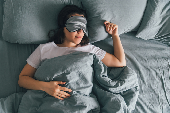 woman sleep in eye patch in grey bed. copy space