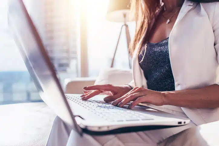 Close-up image of female hands typing on laptop keyboard in modern office Close-up image of female hands typing on laptop keyboard in modern office