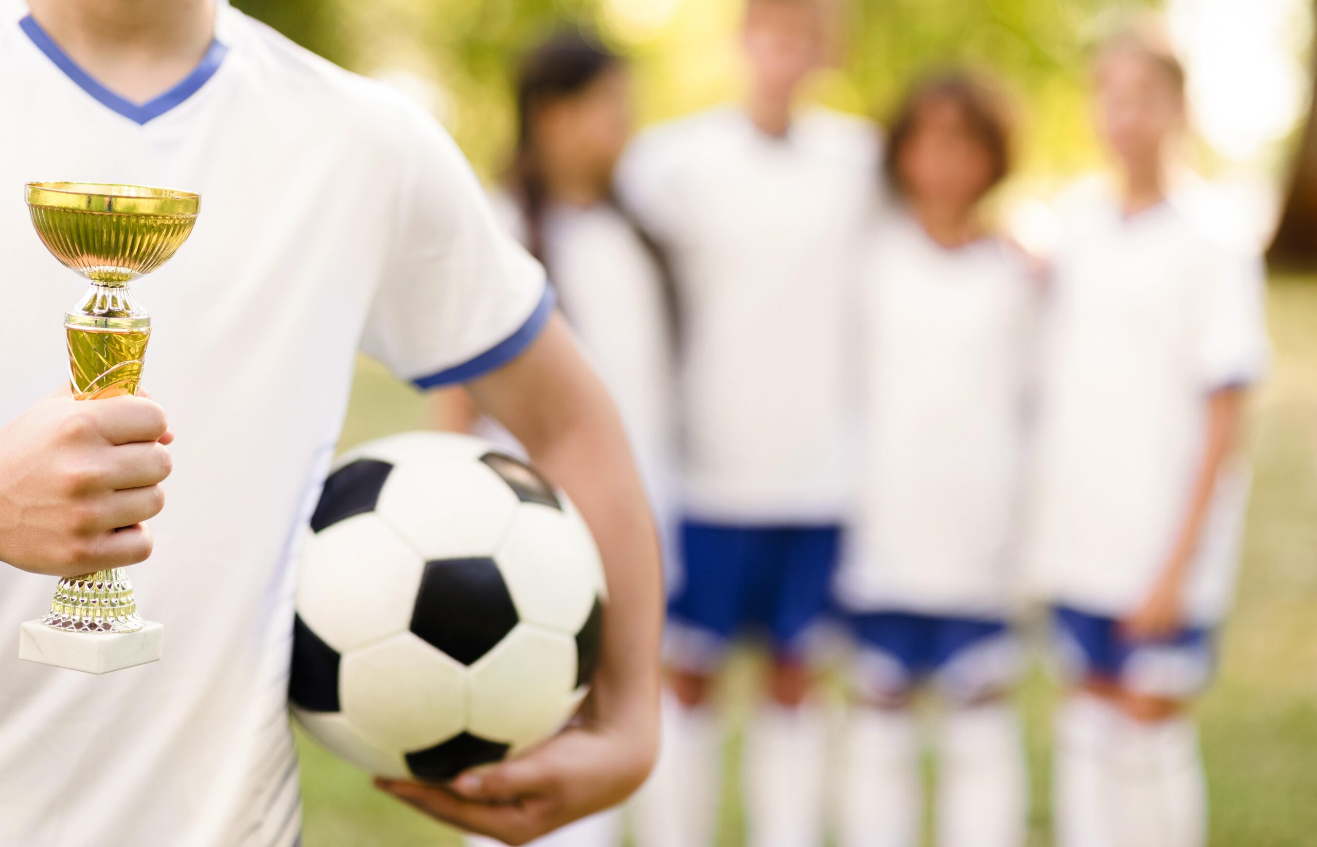 boy-holding-golden-trophy-his-team-mates-unfocused